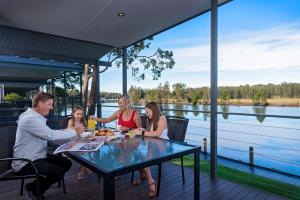 a family sitting at a table on the deck of a boat at Discovery Parks - Forster in Tuncurry