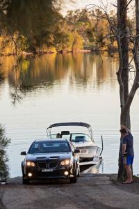 a car parked next to a boat on a lake at Discovery Parks - Forster in Tuncurry