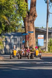 a group of children riding on toy cars down a street at Discovery Parks - Forster in Tuncurry