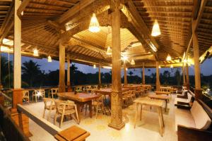 un restaurante con mesas de madera, sillas y luces en Pondok Sebatu Eco Lodge en Tegalalang