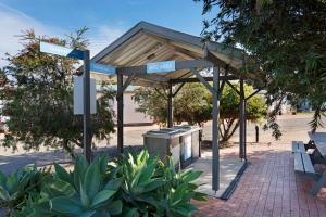a bus stop with street signs in a park at Discovery Parks - Forster in Tuncurry