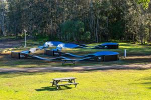 a picnic table in a field with a park with tents at Discovery Parks - Forster in Tuncurry