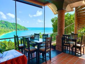 un patio con mesa, sillas y el océano en Sea Breeze Resort - SHA Plus en Haad Rin
