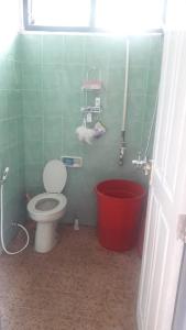 a bathroom with a toilet and a red bucket at Villa Sahala Simanjuntak in Balige