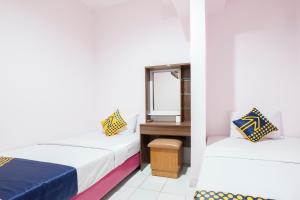 two beds in a room with a mirror at SPOT ON 2214 Wisma Jampea in Makassar