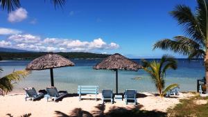 Savaii Lagoon Resort في Fagamalo: مجموعة من الكراسي والمظلات على الشاطئ