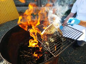 a man cooking food on a grill with flames at Sanyoso in Tosa