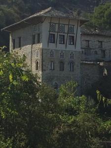 un antiguo edificio de piedra con ventanas en una colina en Konaku Guest house, en Gjirokastra