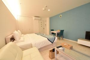 a bedroom with a bed and a couch and a table at Pine Hills Hotel Miyakojima in Miyako-jima