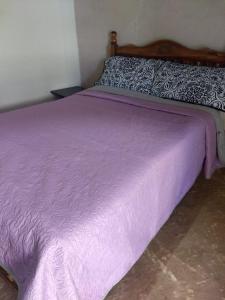 ein Bett mit einer lila Decke darüber in der Unterkunft Miroji in Zacatlán