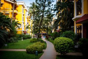 a walkway through a park with palm trees and buildings at Adamo The Bellus in Calangute