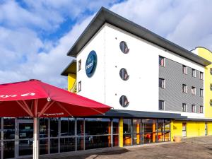 ein Hotel mit einem roten Regenschirm vor einem Gebäude in der Unterkunft Hotel Rhynern Nord in Rhynern