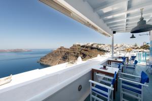 un restaurante con sillas azules y vistas al océano en Vallas Apartments & Villas en Firostefani