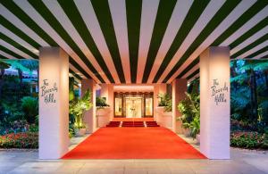 un tapis rouge menant à la porte d'entrée d'un bâtiment dans l'établissement The Beverly Hills Hotel - Dorchester Collection, à Los Angeles