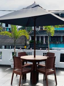 a wooden table with chairs and an umbrella at El Corazon De Hikkaduwa in Hikkaduwa