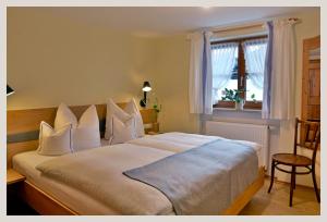 a bedroom with a large white bed with a window at Landhaus Marie-Theres in Oberstdorf