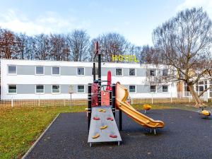 a playground with a slide in front of a building at Hotel Göttingen-West in Rosdorf