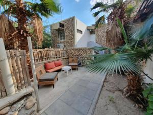 a patio with a couch and chairs and a fence at Adam s apartments entrance to Neve Zohar in Neve Zohar