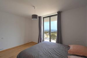 ein Schlafzimmer mit einem Bett und einem großen Fenster in der Unterkunft Bel appartement vue mer Porto Vecchio in Porto-Vecchio
