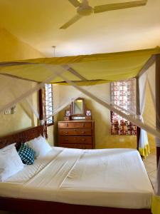 - une chambre avec un lit à baldaquin et une commode dans l'établissement Flametree Beach Homes, à Diani Beach