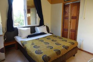 1 dormitorio con cama, ventana y espejo en Cheers Guesthouse, en Botianaw