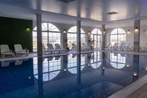 a pool in a building with chairs and a table at Villa Della Rosa in Razgrad
