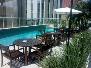 a patio with tables and chairs next to a pool at Aparthotel Condomínio Mondial in Salvador +21 photos
