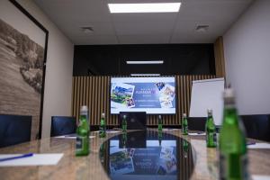 a conference room with a table and a projection screen at Hotel Avangarda in Różan