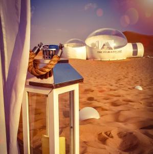 Blick auf eine Wüste mit einem Zelt und einem Surfbrett in der Unterkunft STARLIGHT CAMP in Dubai