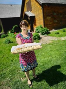 a woman is holding a tray of pizza at Zagroda Ziołowy Dzbanek in Młynary