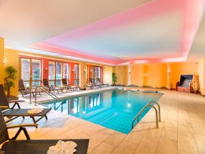 una piscina en una habitación de hotel con sillas en SCOL Sporthotel Großglockner en Kals am Großglockner