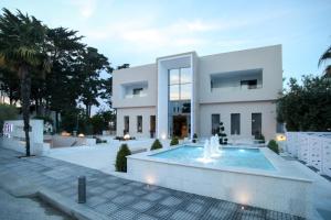 a large white house with a fountain in front of it at Naias in Hanioti