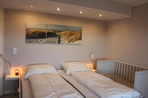 two beds in a bedroom with two paintings on the wall at Augustenhof Ferien in Nordborg