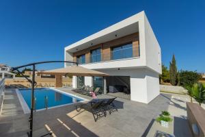 a villa with a swimming pool and a house at Villa Andre, walking distance to Coral Bay in Peyia