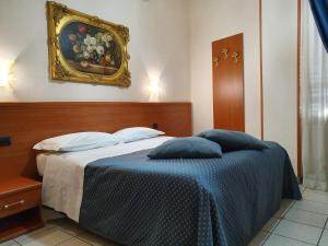 a bedroom with a bed with a painting on the wall at Hotel San Giorgio in Bergamo