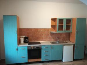 a kitchen with blue cabinets and a sink at Sümegi Levendula Apartmanok in Sümeg