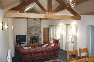 een woonkamer met een rode bank en een open haard bij Sygun Cottage - Detached Cottage in the heart of the Snowdonia National Park in Beddgelert