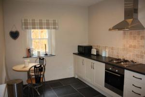 a kitchen with a table and a stove top oven at Sygun Cottage - Detached Cottage in the heart of the Snowdonia National Park in Beddgelert