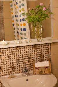 a bathroom sink with a vase of flowers on a mirror at Grekis Beach Hotel and Apartments in Petalidi