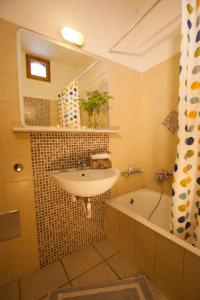 a bathroom with a sink and a bath tub at Grekis Beach Hotel and Apartments in Petalidhion