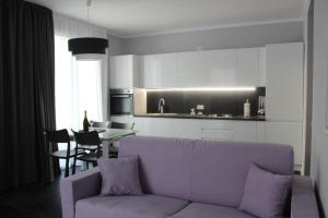 een woonkamer met een paarse bank en een keuken bij Abelia 4 in Pietra Ligure