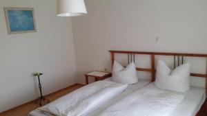 een slaapkamer met 2 bedden met witte lakens en kussens bij Weingut Landmann Ferienwohnungen in Freiburg im Breisgau