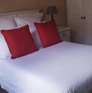 Una cama blanca con dos almohadas rojas. en El Shaddai, en Darling