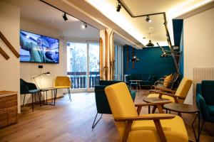 a living room with yellow chairs and a flat screen tv at Roomie Alps Design Hostel in Kitzbühel