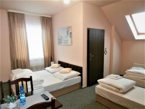 シュチルクにあるZajazd Sumのベッド2台、テーブル、ドアが備わる客室です。