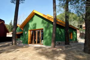 zielony dom z brązowym dachem i drzewami w obiekcie Complejo Casas Rurales MANSIONES Y VILLAS DELUXE w mieście Collado Mediano