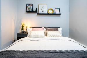 um quarto com uma cama com lençóis brancos e almofadas em Kensington Modern Apartment em Londres