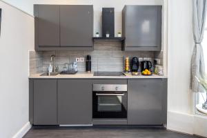 uma cozinha com armários cinzentos e um forno em Kensington Modern Apartment em Londres