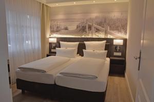 a bedroom with a large bed with a painting on the wall at Fisher's Inn in Zingst