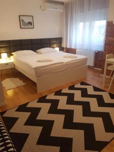 a bedroom with a large bed and a rug at HOME APARTMANI I SOBE in Osijek
